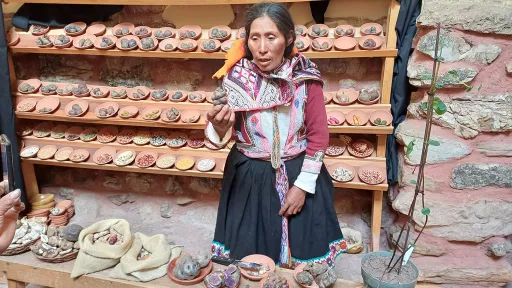 A woman standing in front of shelves full of potatoes at an outdoor stall.