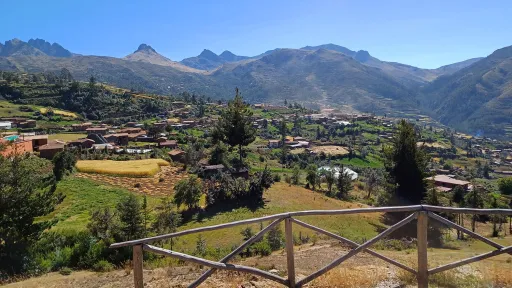 A scenic view over green hills to mountains in the background under a blue sky.