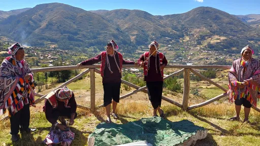 People learn on a wooden rail with a scenic view of mountains behind.